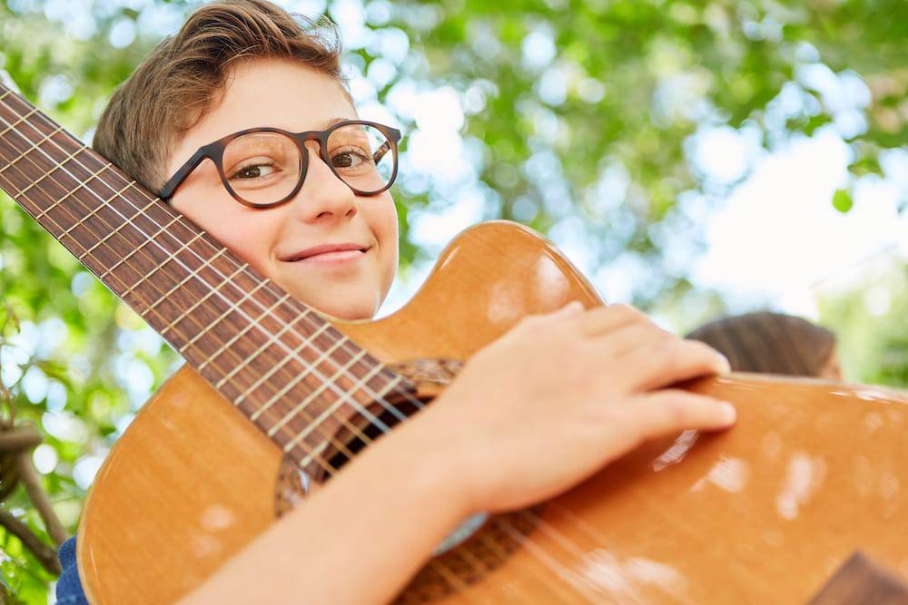 A boy plays the guitar outdoors