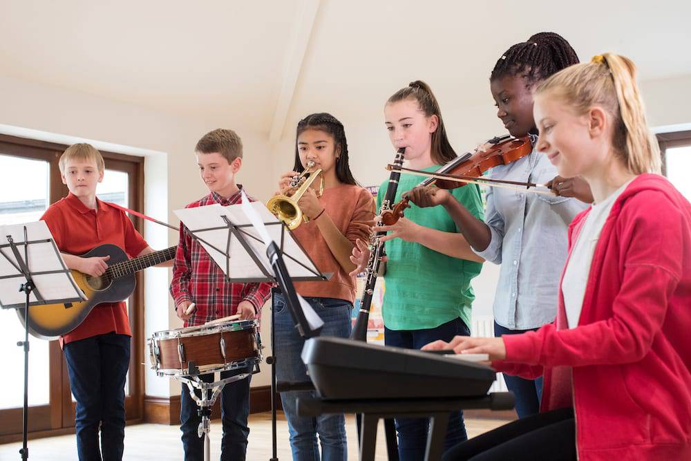 A group of young musicians playing together in a band as part of their face to face and online music education