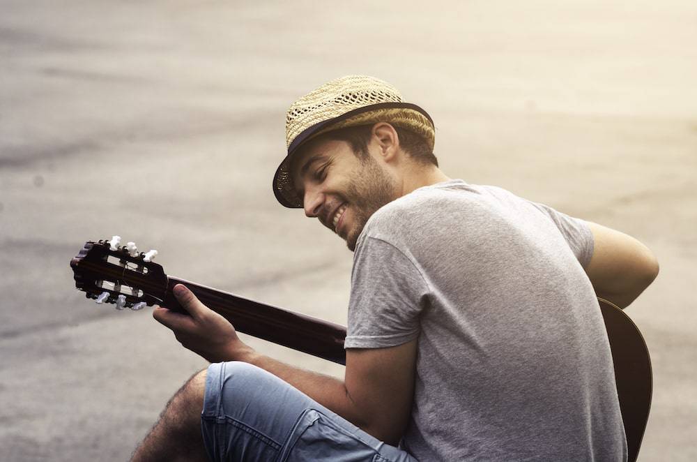 A happy man playing a guitar outdoors