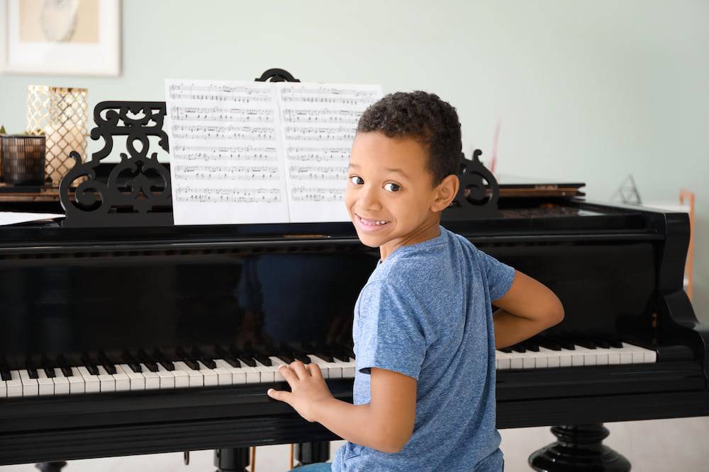 A happy young boy learning the piano in his living room