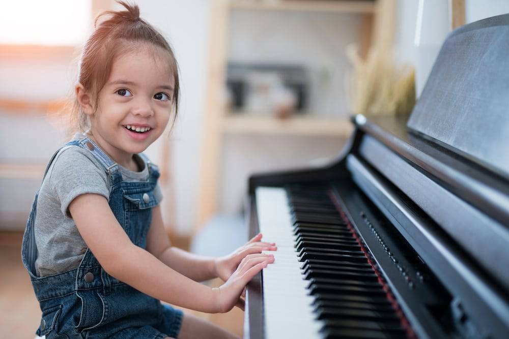 A little girl practices the piano at home