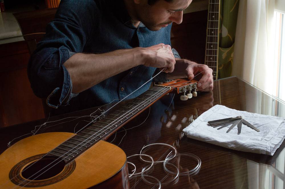A man works on replacing the strings of his guitar