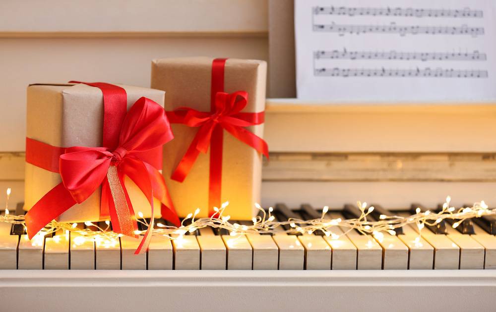 Presents resting on a piano with Christmas lights