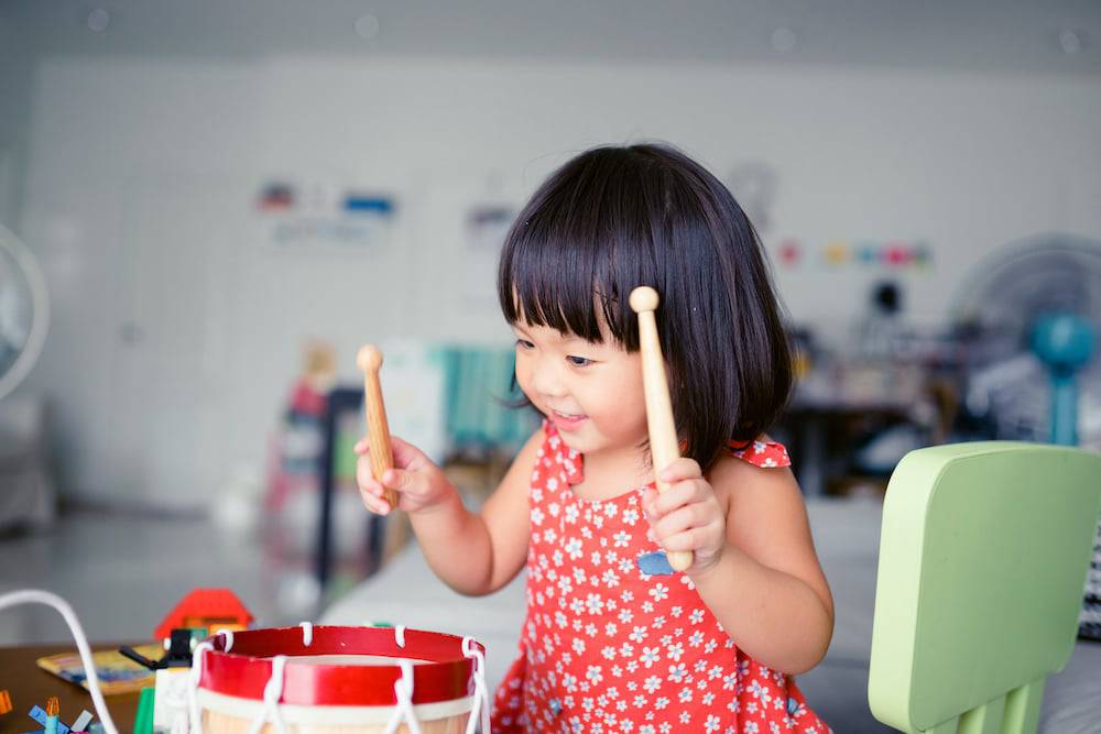 A young girl plays on her drum set