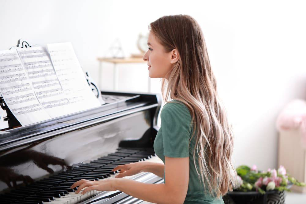 A smiling young woman playing the piano at home