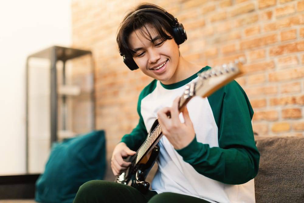Teen boy playing the guitar and wearing headphones