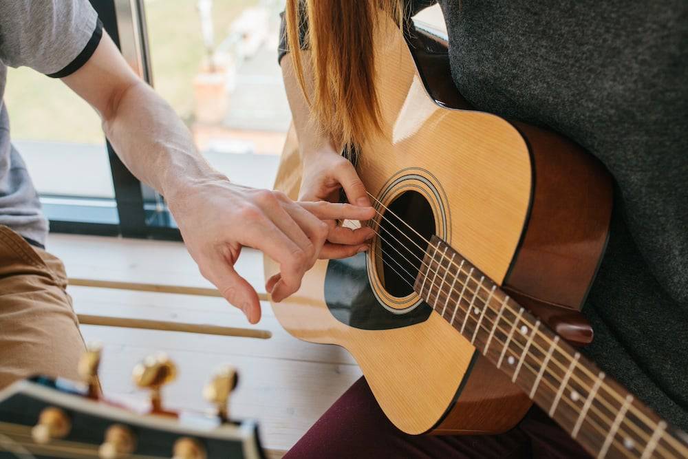 A teenage girl takes guitar lessons
