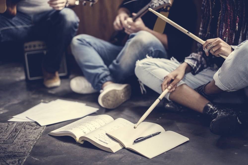 Teens sitting together playing music and writing songs