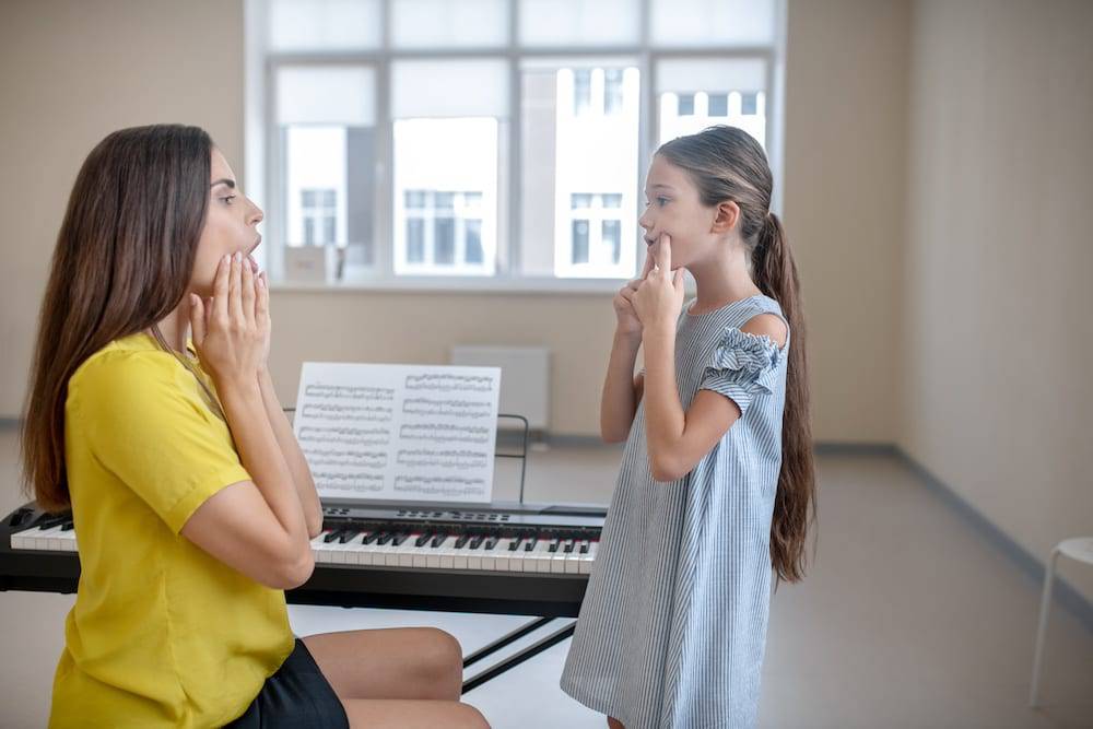 A woman teaches voice lessons in Kansas City to a young girl
