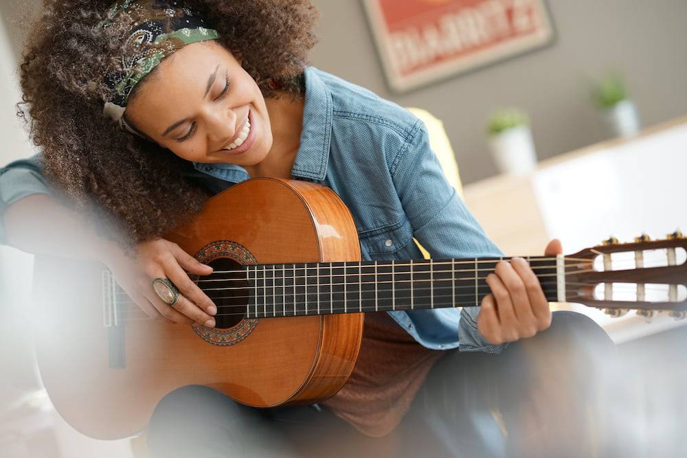 A happy young woman playing guitar