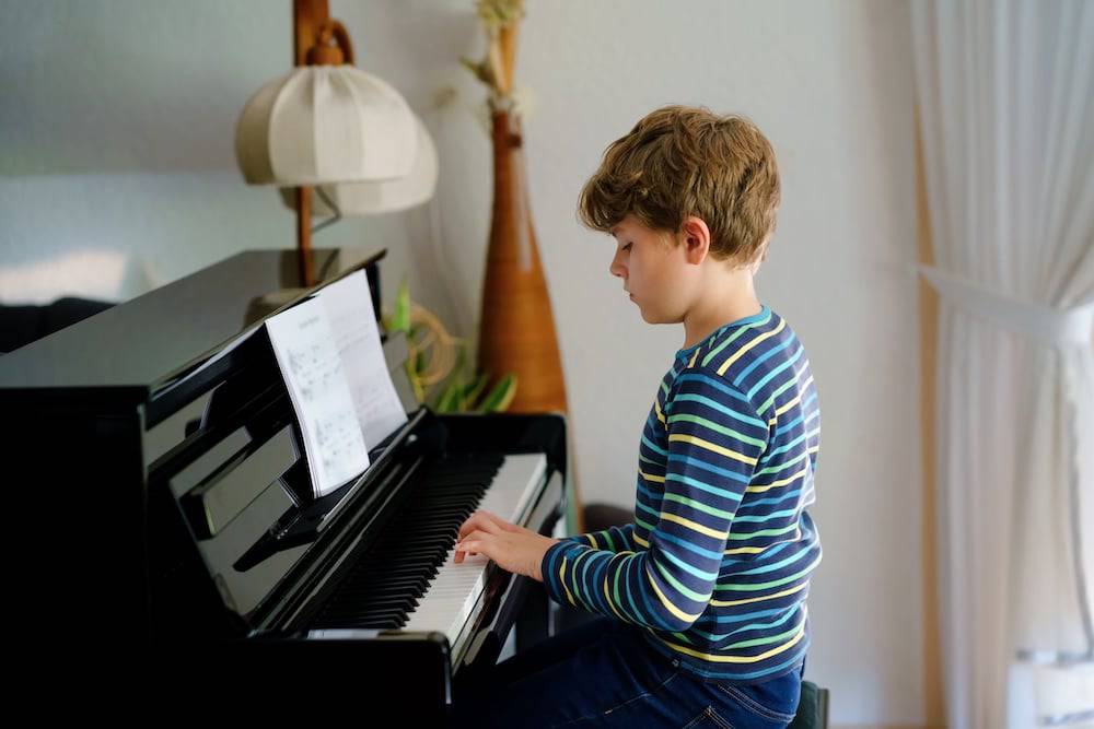 A young boy plays his piano at home