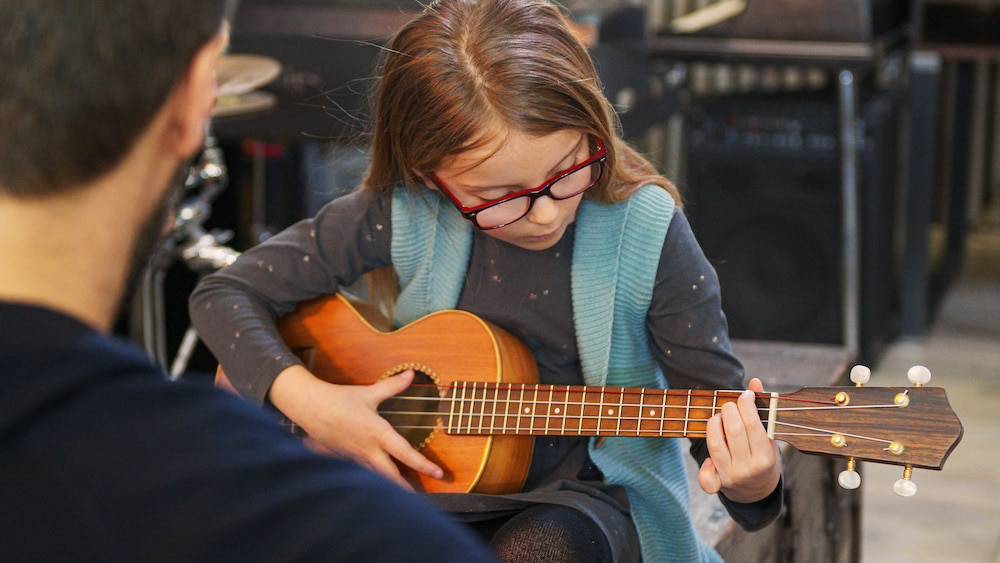 A young girl attending guitar lessons in Overland Park