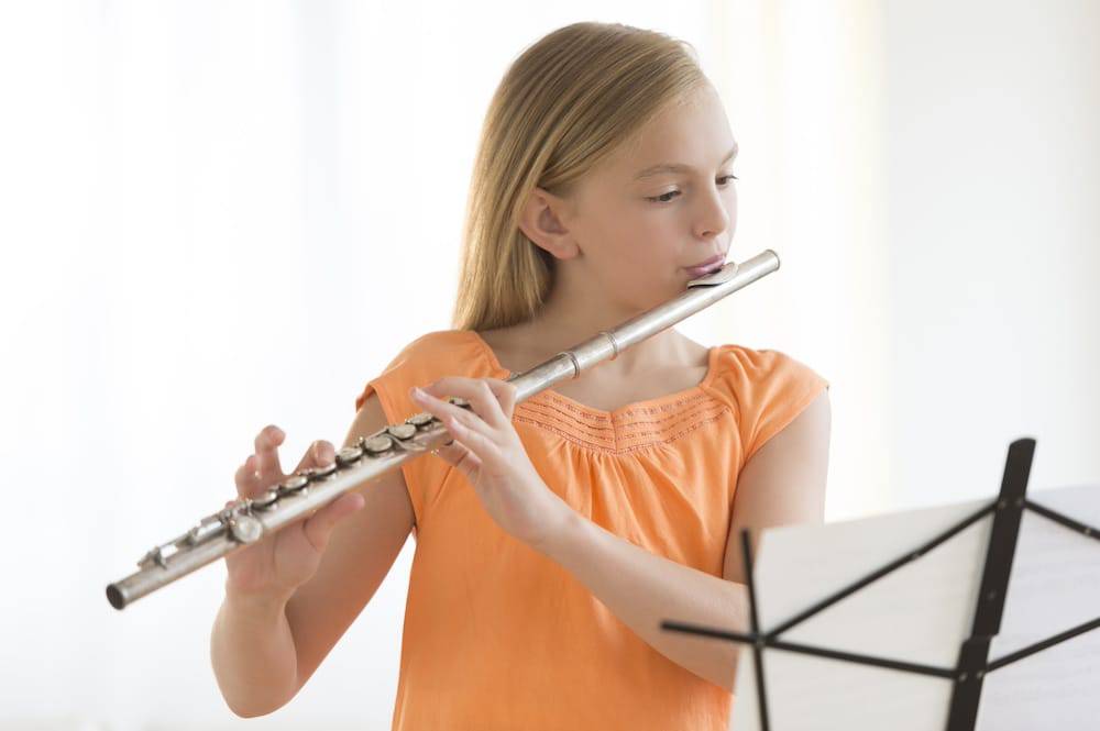 A young girl practicing the flute at a music school near me