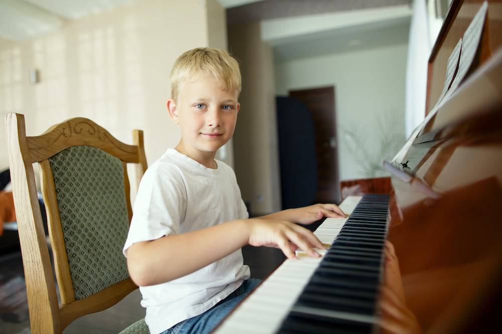 A young boy smiling while playing the piano