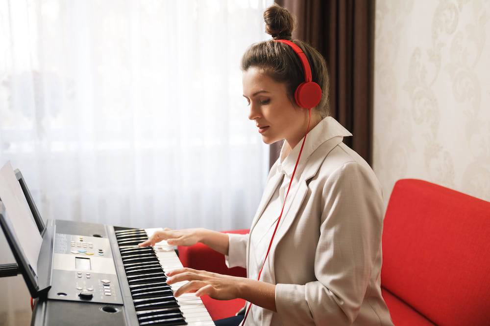 A young woman plays the keyboard in her apartment
